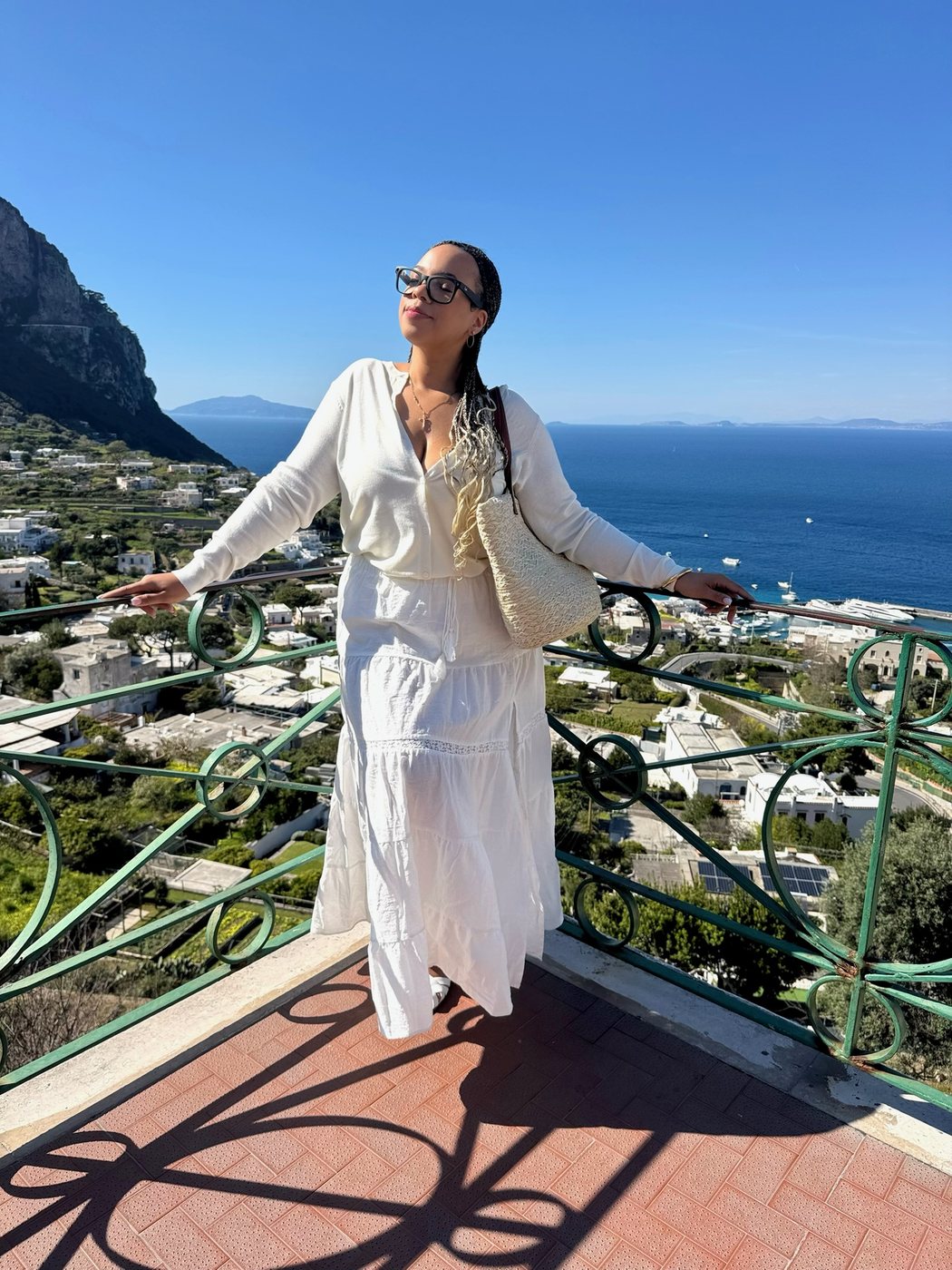 Delanna in a white linen set on a terrace above the sea