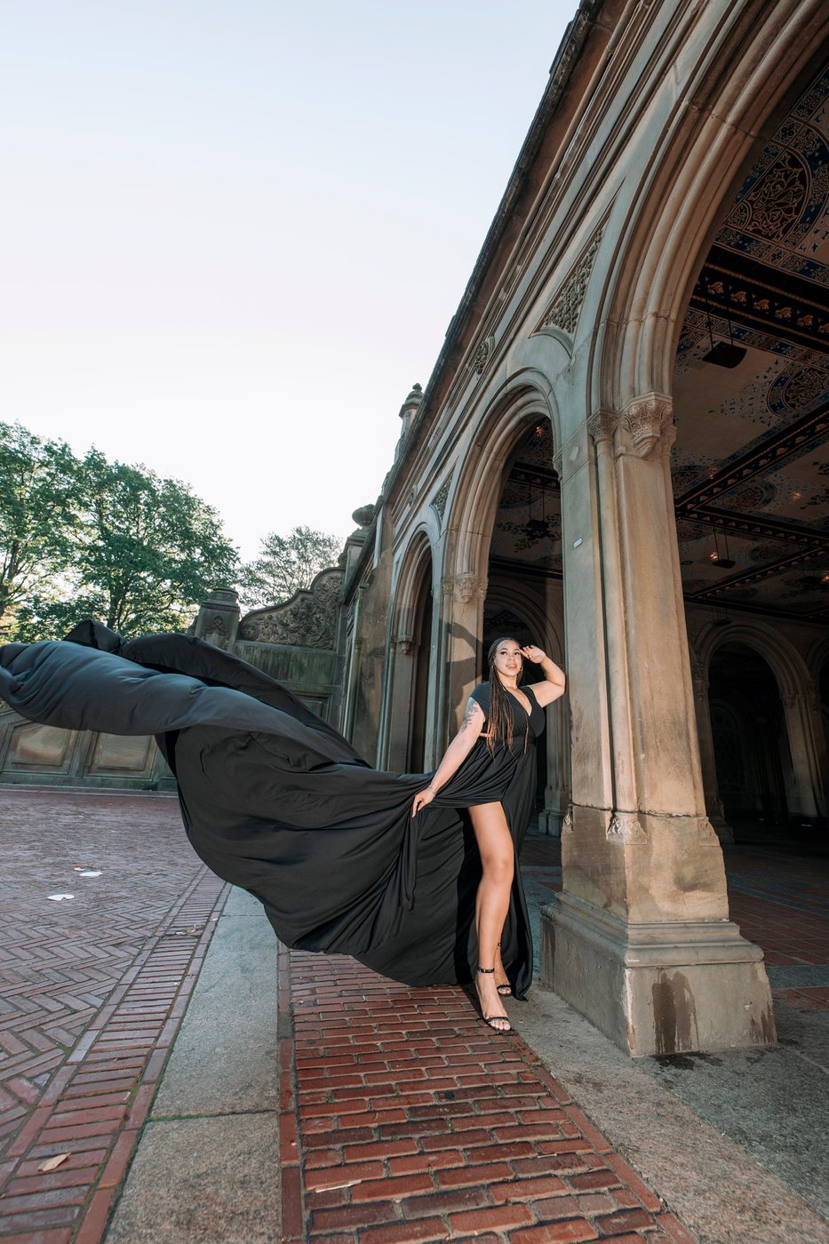 Delanna in a long black gown caught mid-flow beneath the stone arches at Bethesda Terrace