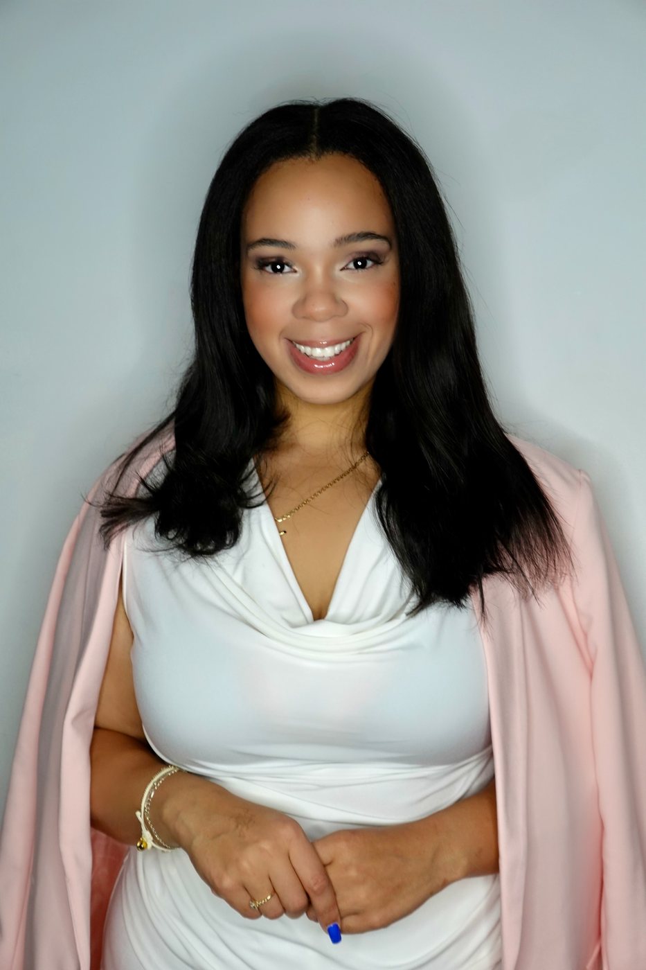 Portrait of Delanna in a white top with a pink blazer draped over her shoulders