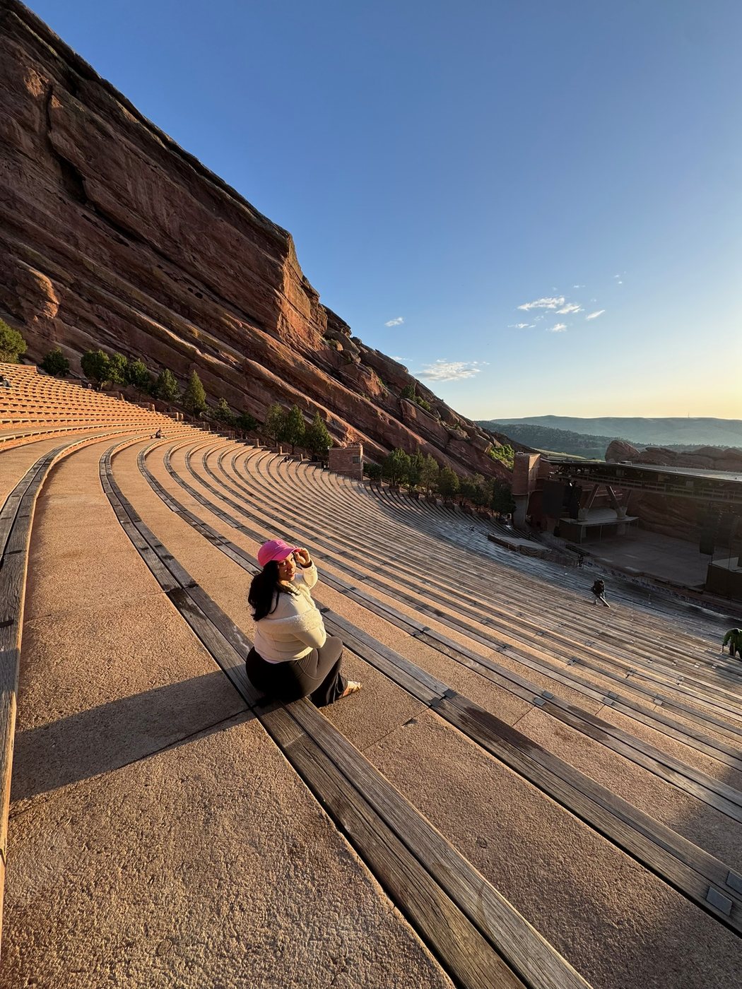 Delanna sitting on the stone seating of a red-rock amphitheater at sunset