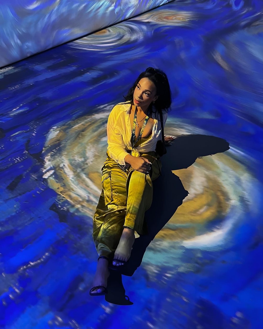 Delanna seated on the floor of an immersive Van Gogh projection room